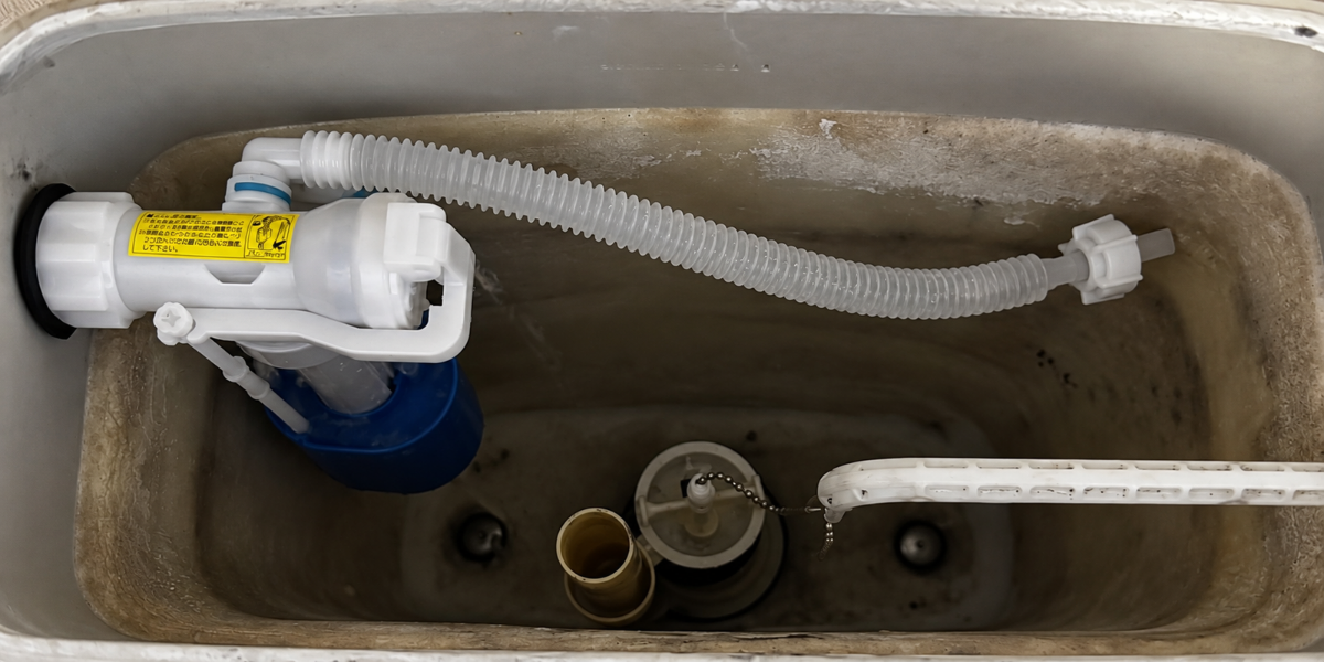 トイレタンクの内部に見える白いボールタップと蛇腹状の給水管