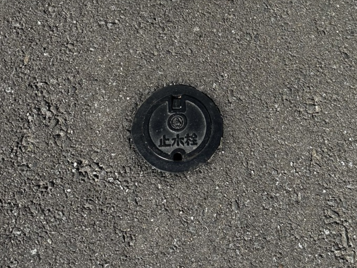 道路のアスファルト上にある「止水栓」と書かれた丸いふた